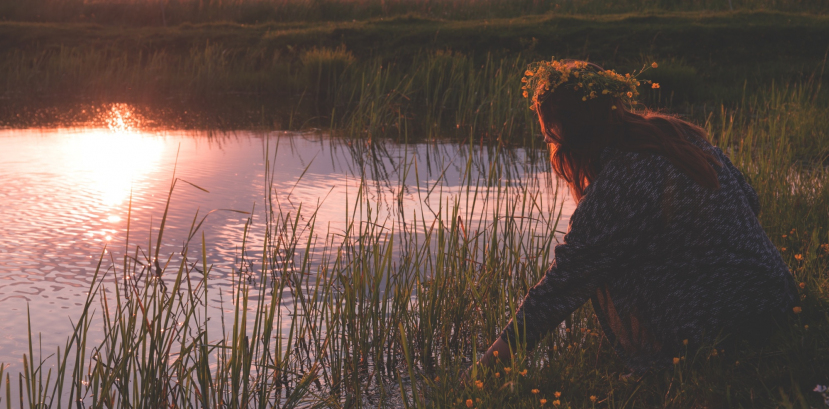 kobieta w wianku na głowie kuca na brzegu jeziora